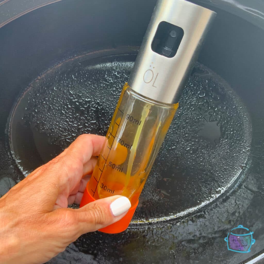 Crockpot with a spray bottle of oil in front of it