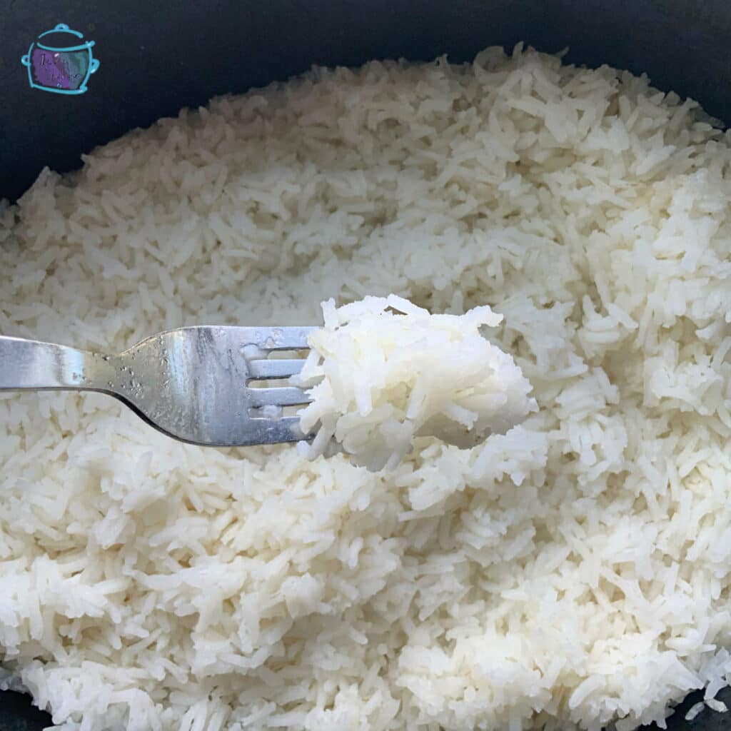 a fork holding some rice of a slow cooker of rice