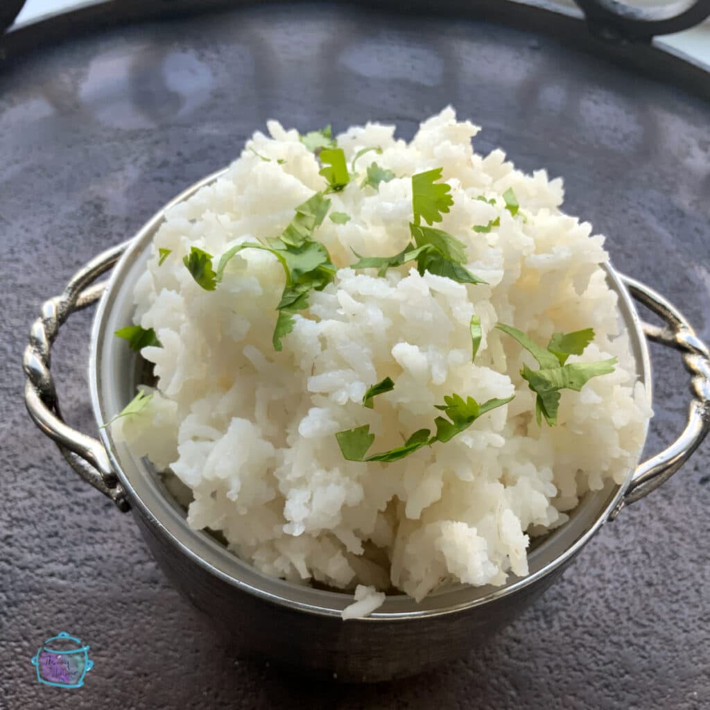 silver bowl of white rice topped topped with fresh chopped cilantro