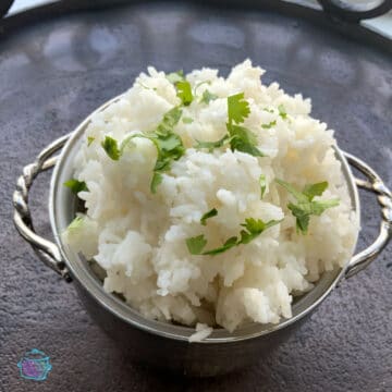 silver bowl of white rice topped topped with fresh chopped cilantro
