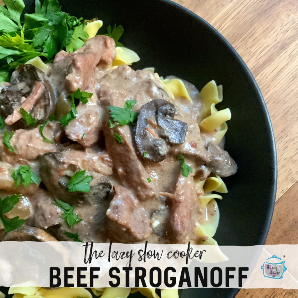 a round black bowl filled with mushroom and beef stroganoff over a bed of noodles