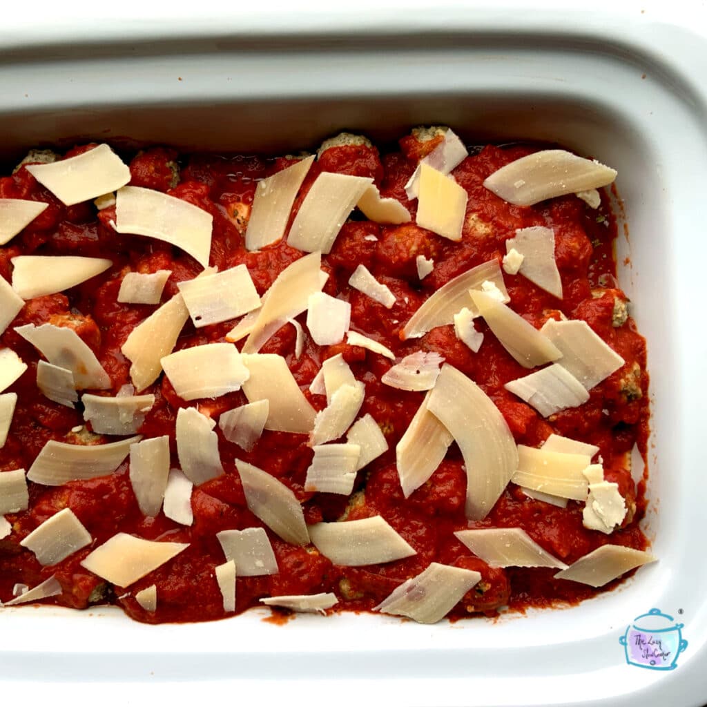 A rectangular slow cooker of meatballs with ravioli before cooking