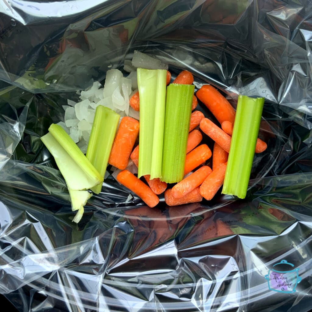 vegetables laying in bottom of a black oval crockpot