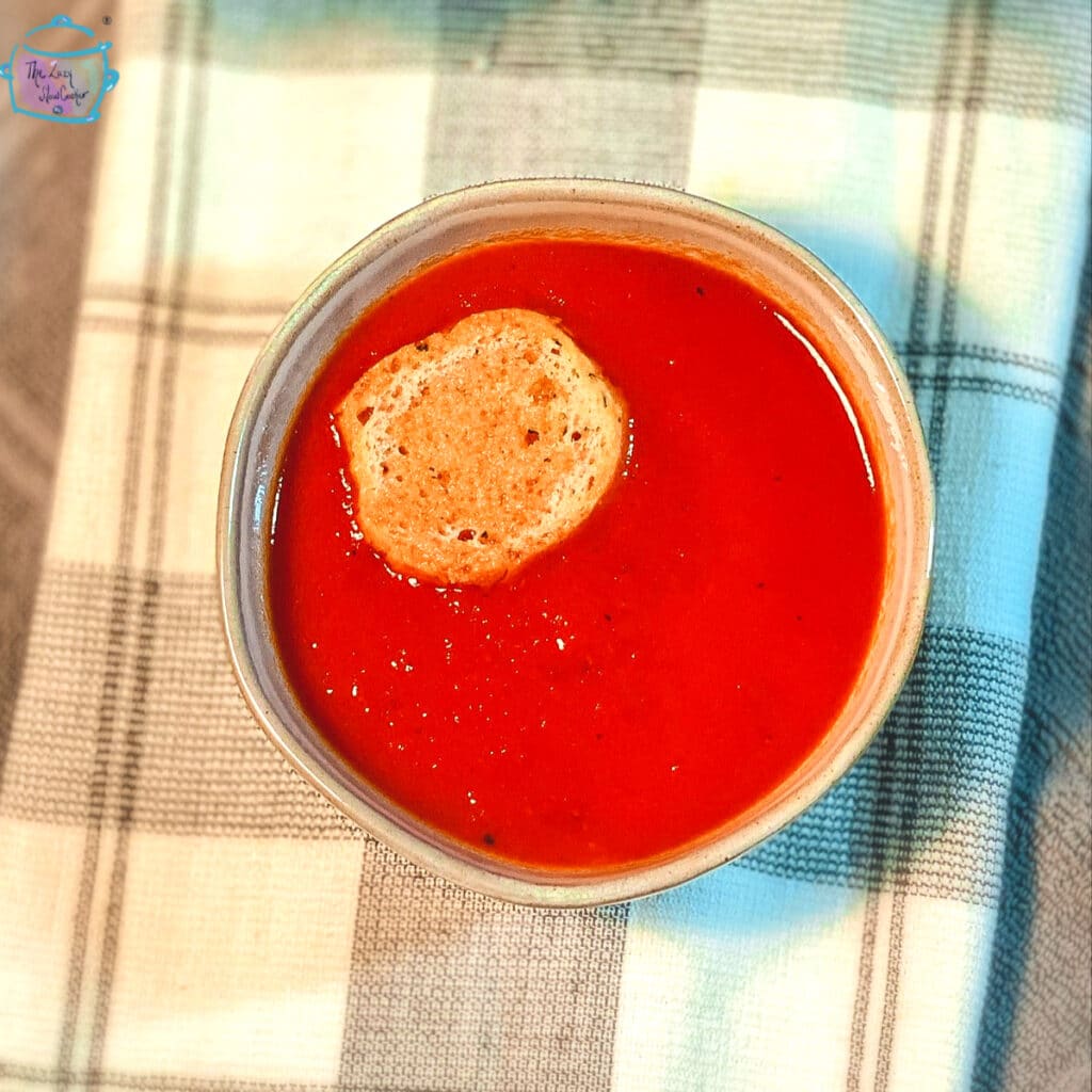 A bowl of tomato soup with a round crouton floating on top