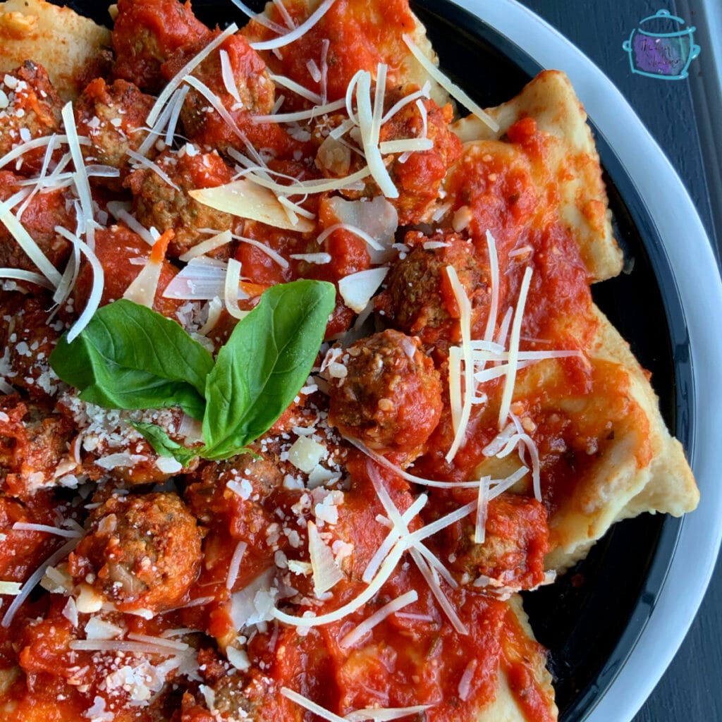 Close up of ravioli and meatballs on a black plate