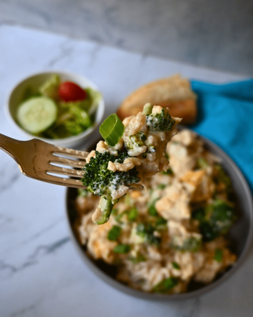 a bowl filled with slow cooker chicken broccoli and rice with a mouthful on a fork