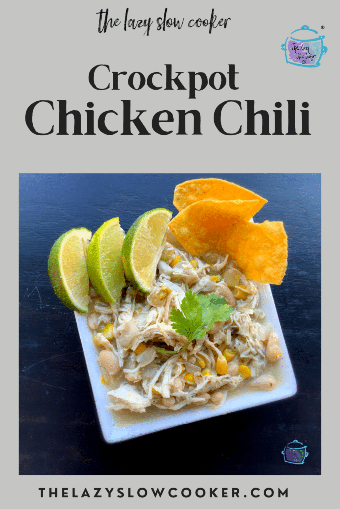 a white bowl filled with dairy free chicken chili garnished with lime wedges and chips