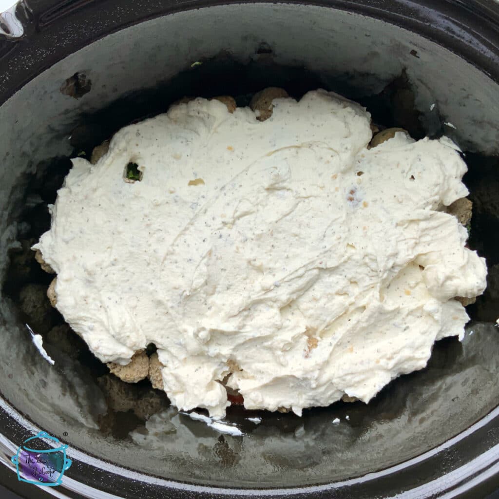 A layer of ricotta mixture spread on top of meatballs