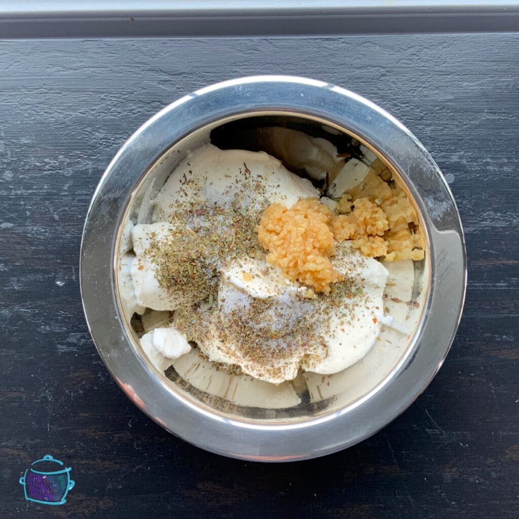 Ricotta cheese with spices in a metal mixing bowl