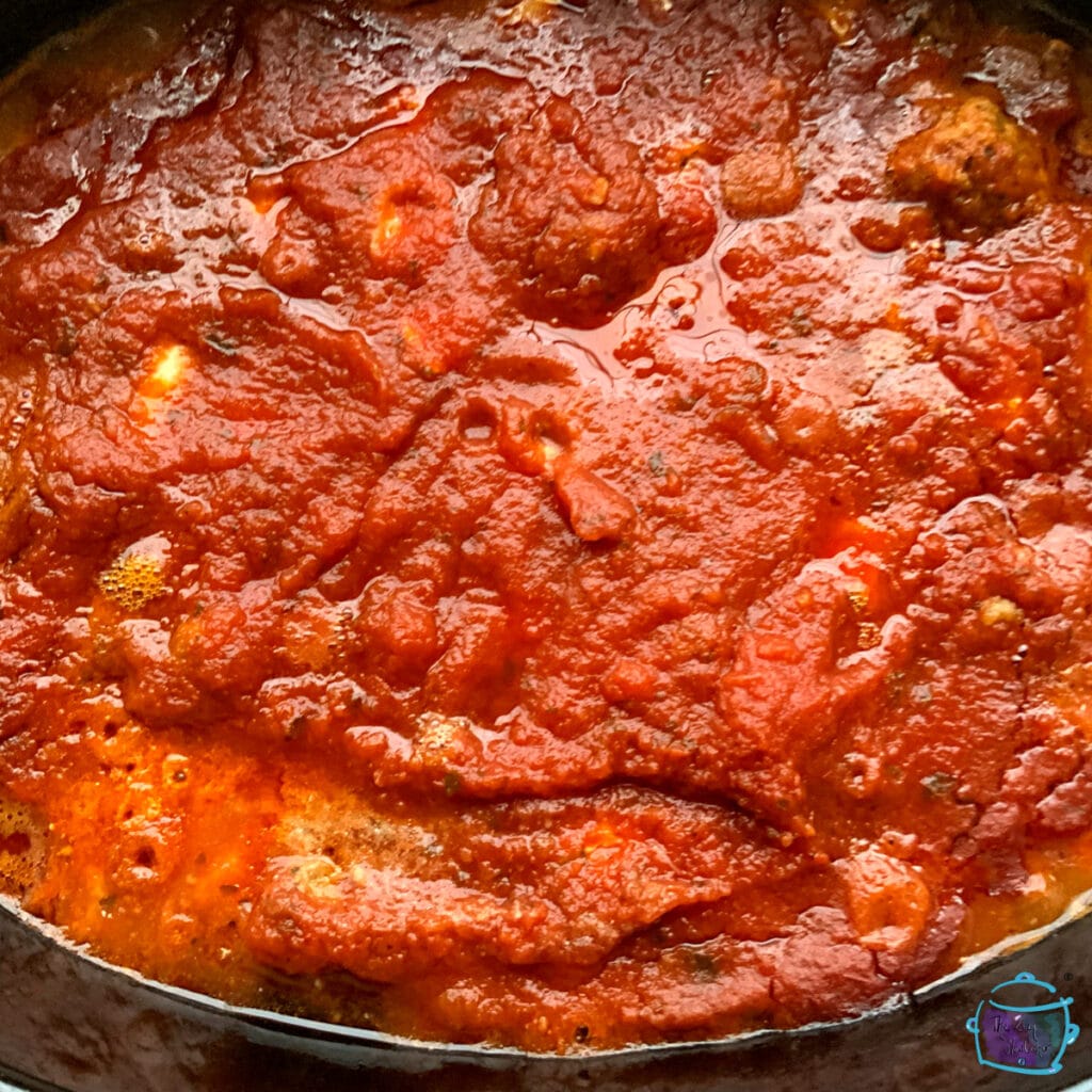 Top view of a slow cooker filled with cooked marinara sauce