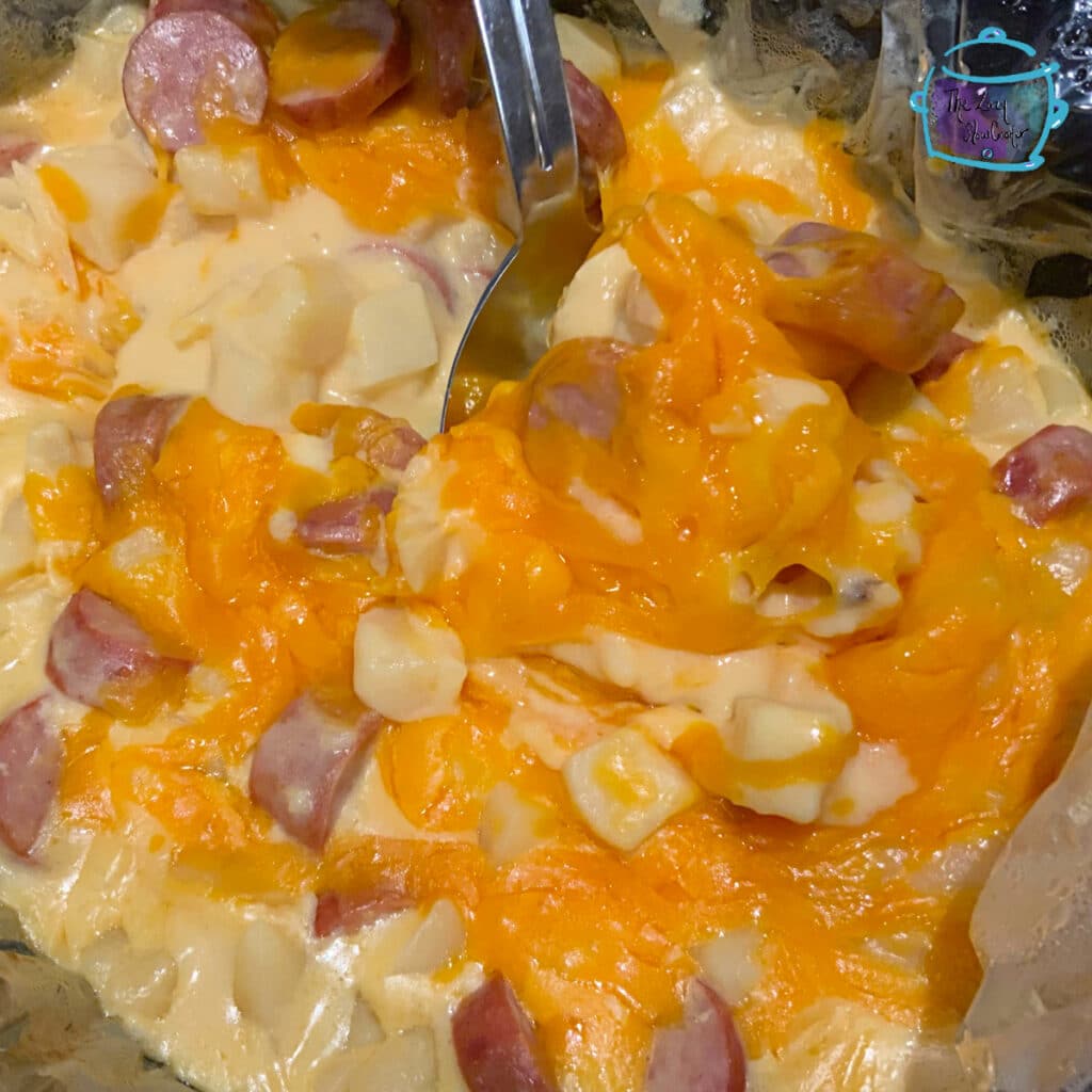 Finished kielbasa dish with cheese melted on top and a serving spoon
