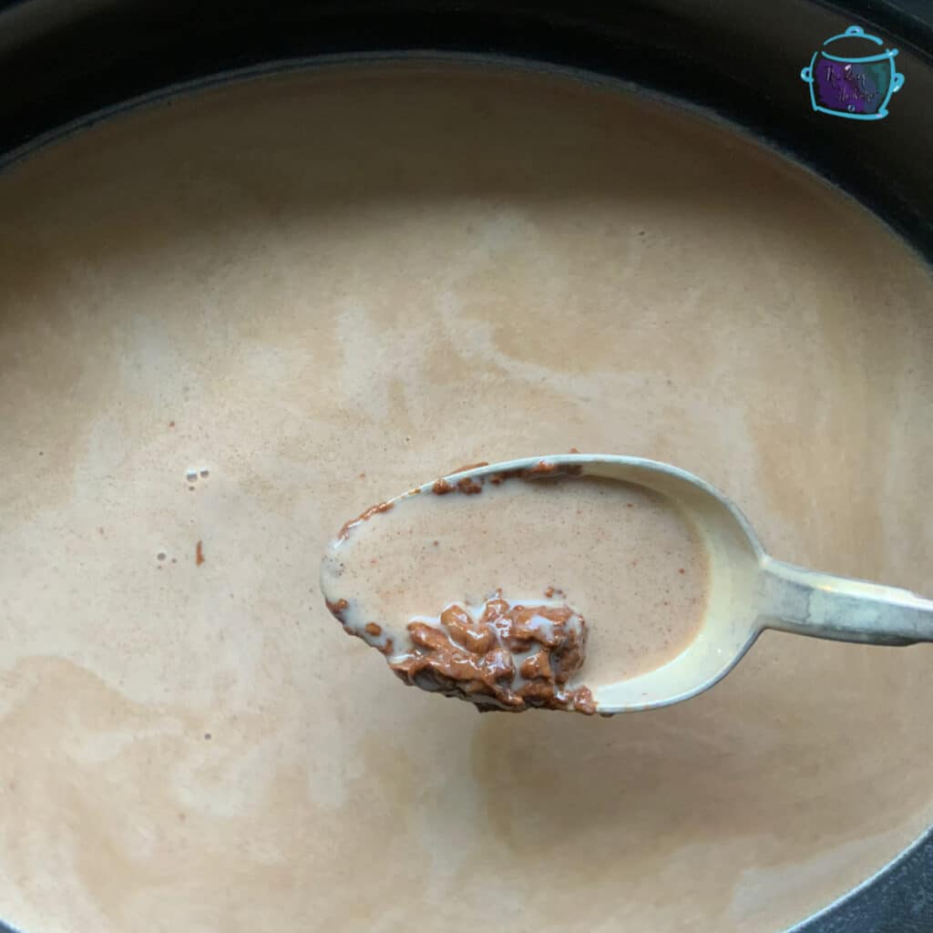 Half melted chocolate chips on a spoon over slow cooker