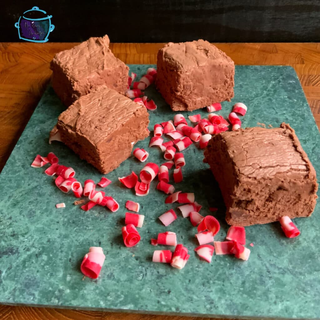 Fudge pieces on a green board with red chocolate shavings around
