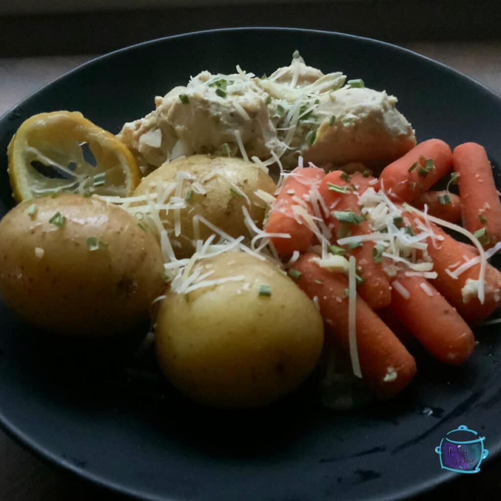 Finished chicken with carrots and potatoes on a black plate