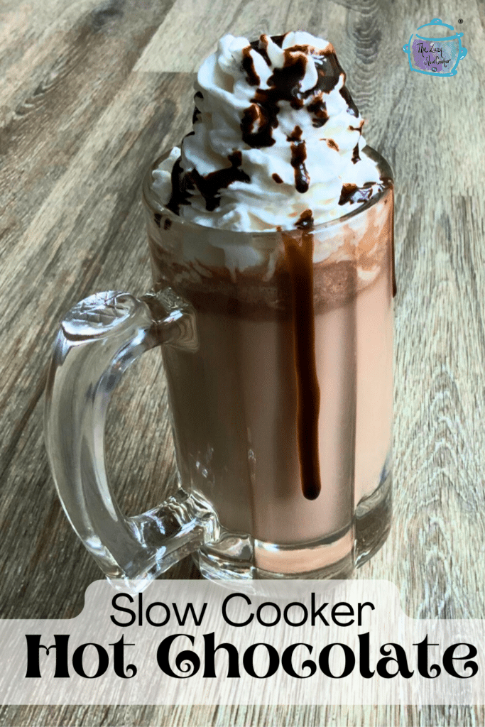 a clear mug filled with hot chocolate topped with whipped cream, sprinkles and chocolate sauce.