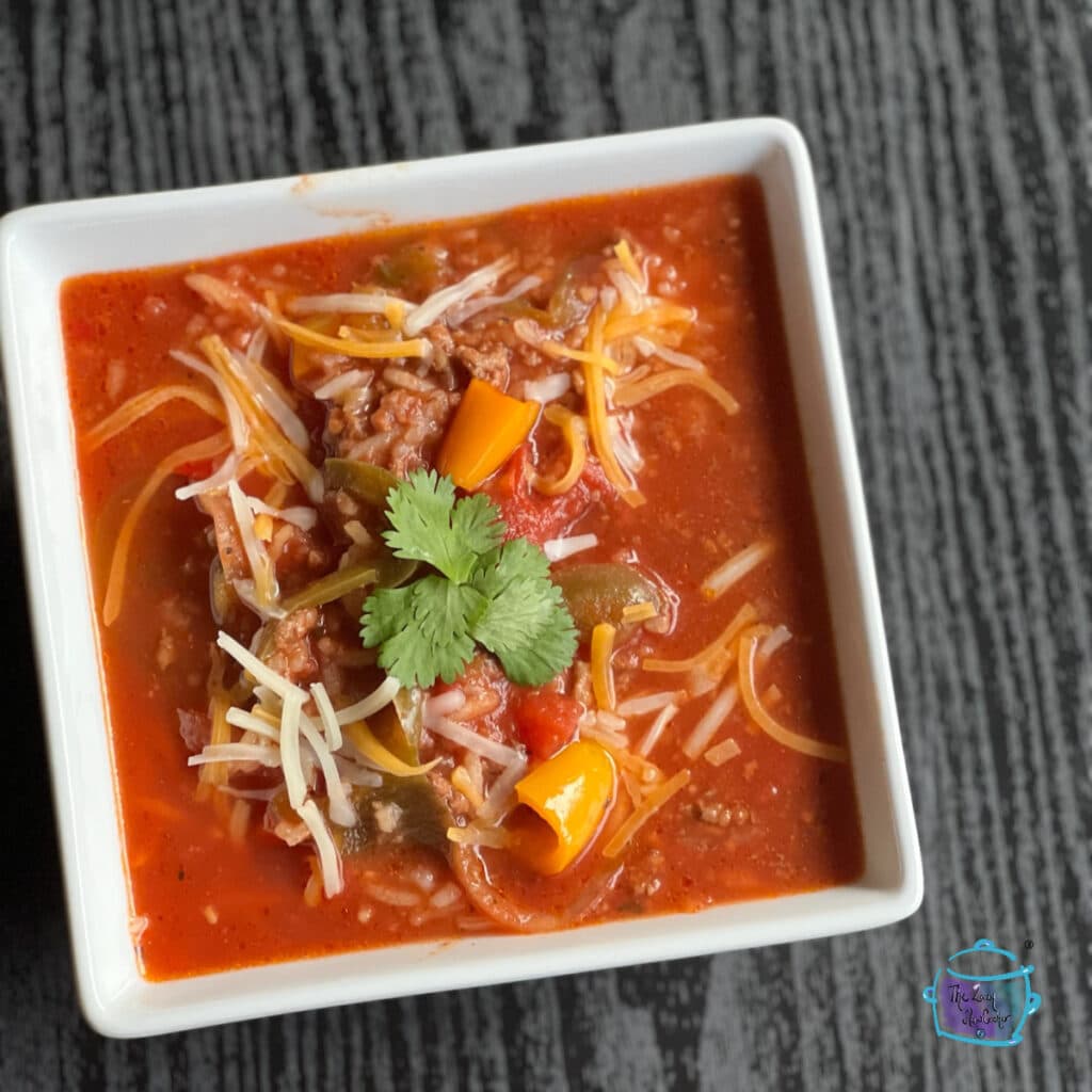 A bowl of pepper soup filled topped with shredded cheese and cilantro