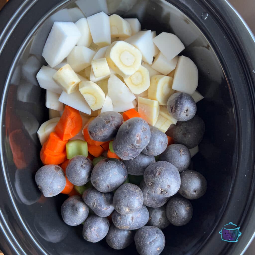 root vegetables and potatoes in slow cooker before cooking
