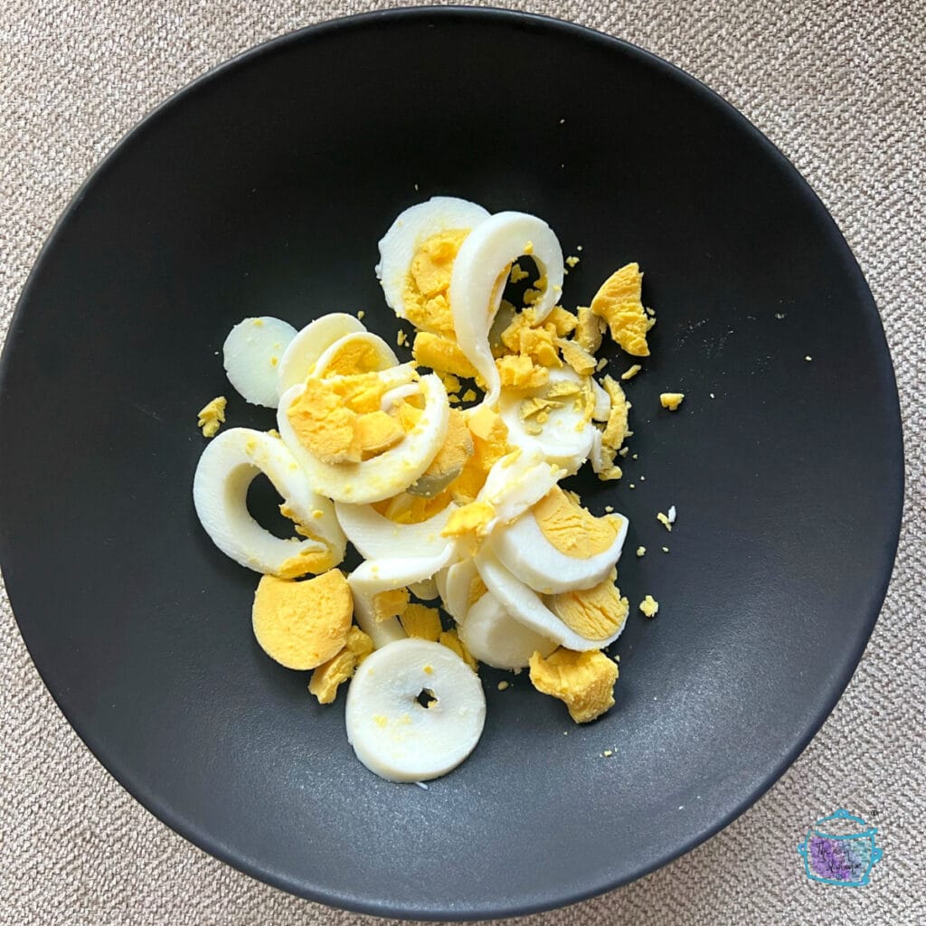 sliced hard boiled egg on a blac plate