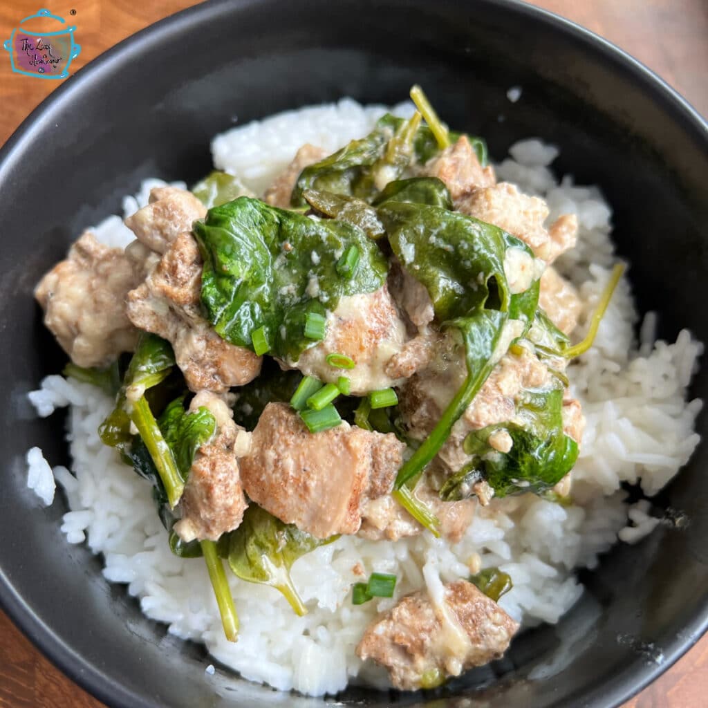 A round black bowl filled with creamy lemon chicken and spinach over rice