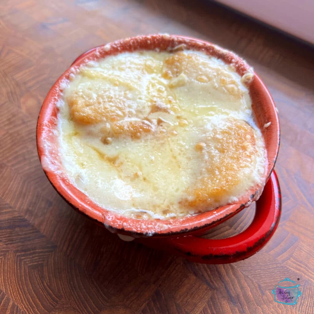 a red crock full of onion soup top with melted cheese
