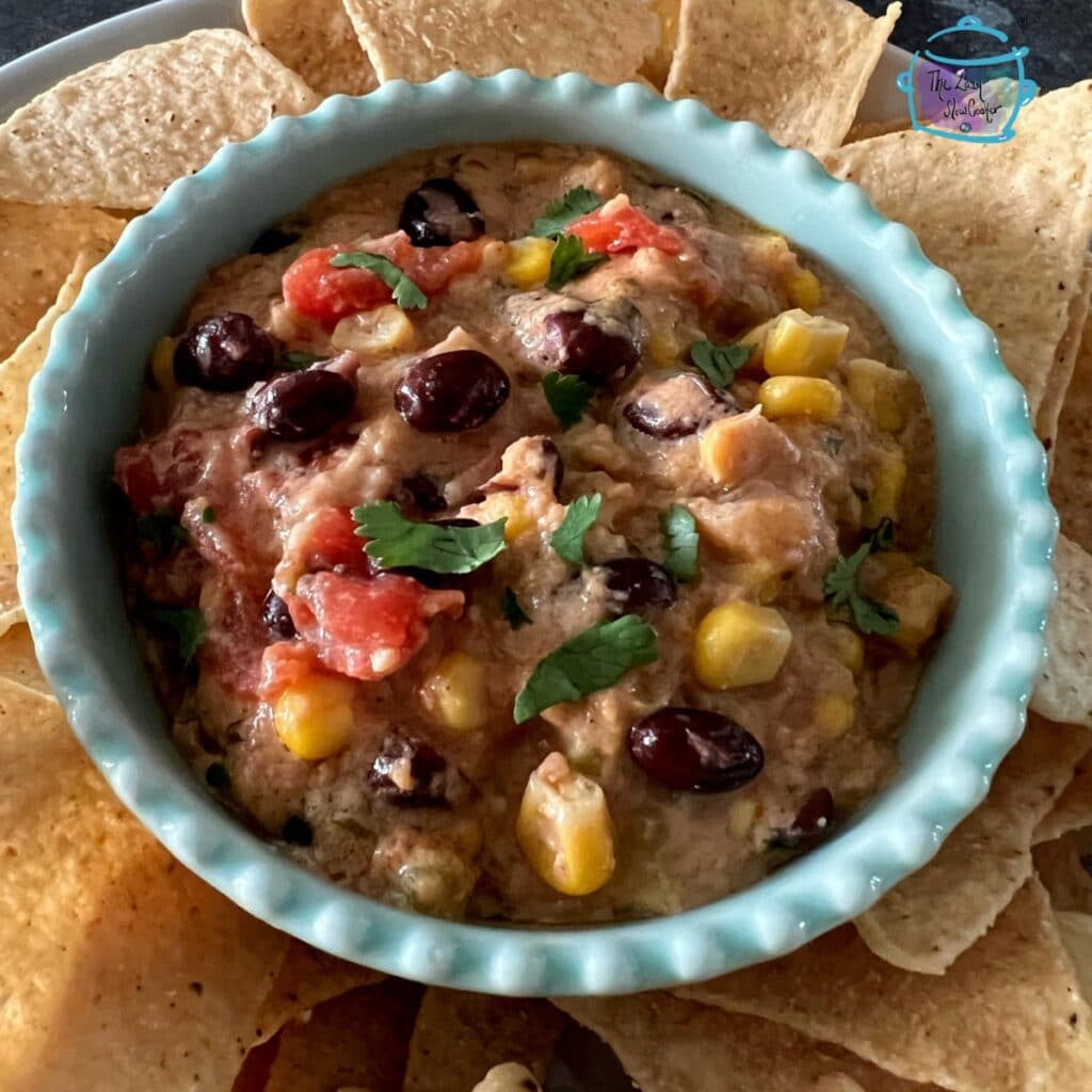 a blue bowl filled with fiesta dip surrounded by tortilla chips