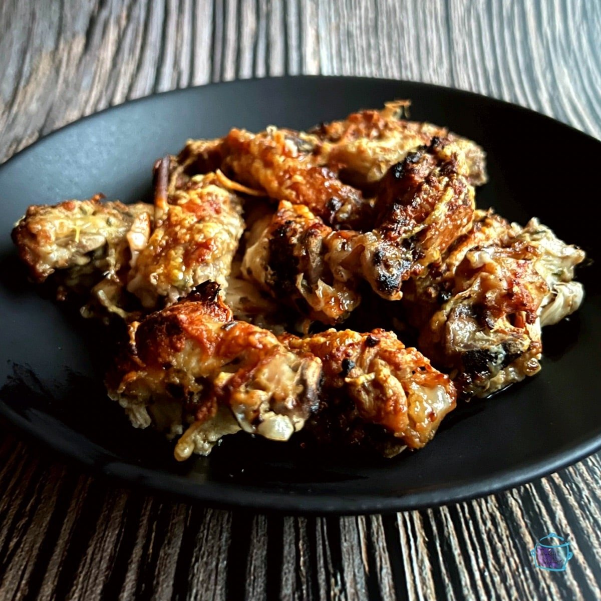 crispy wings displayed on a round black plate