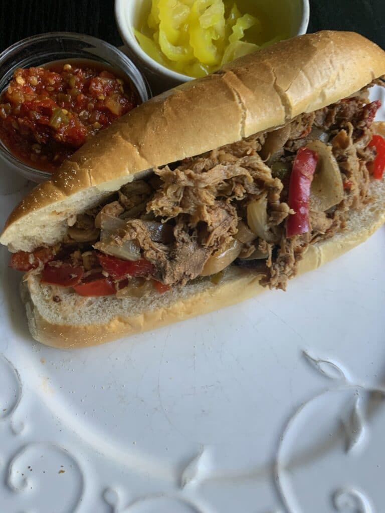 Slow cooker cheesesteak with peppers in the background