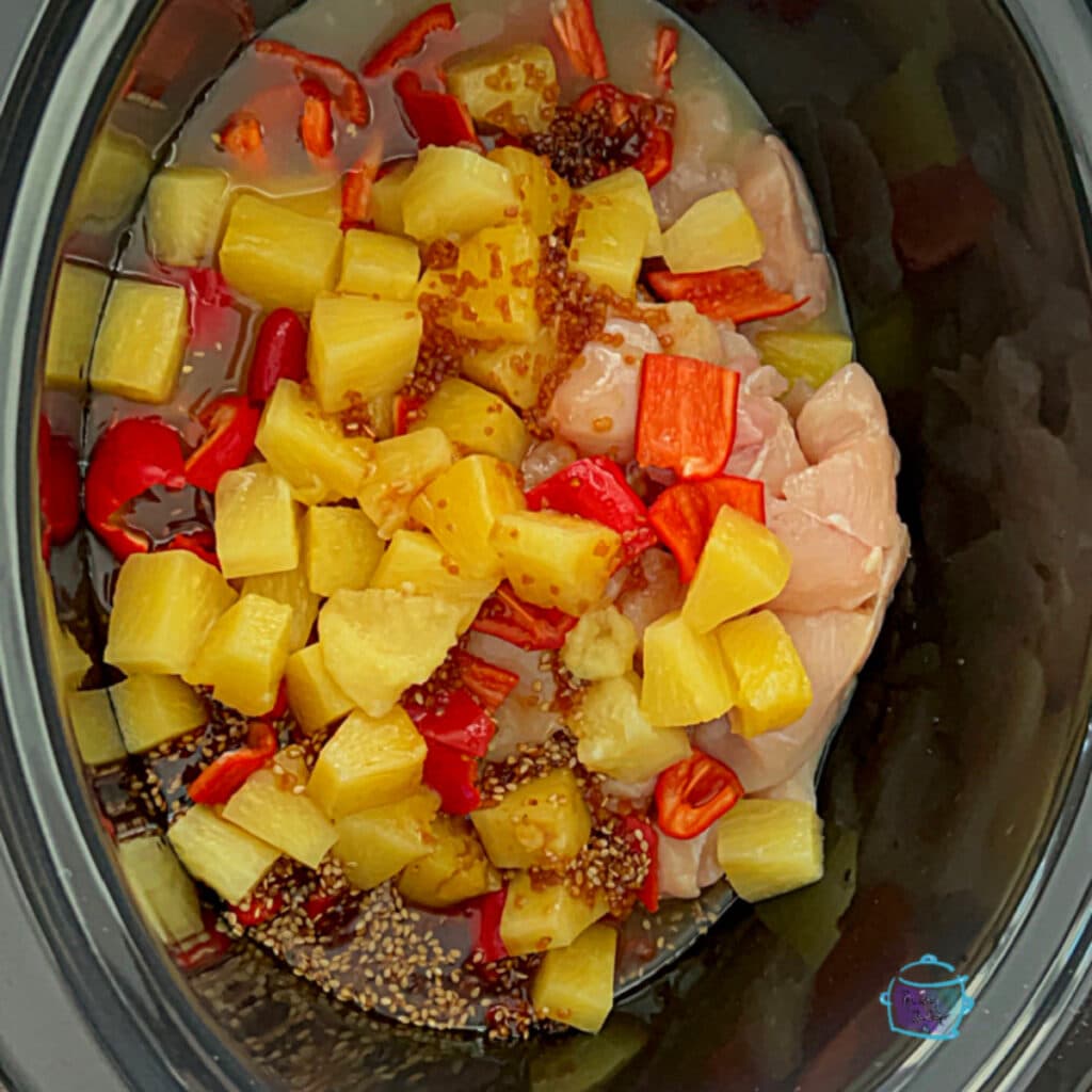 a crockpot full of uncooked pineapple chicken