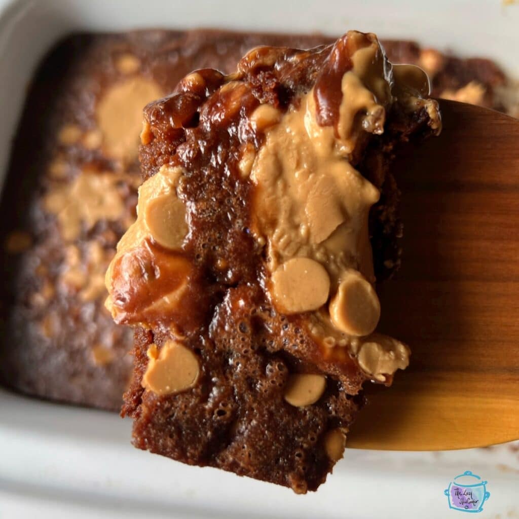 A piece of brownie behind held up by a wooden spoon