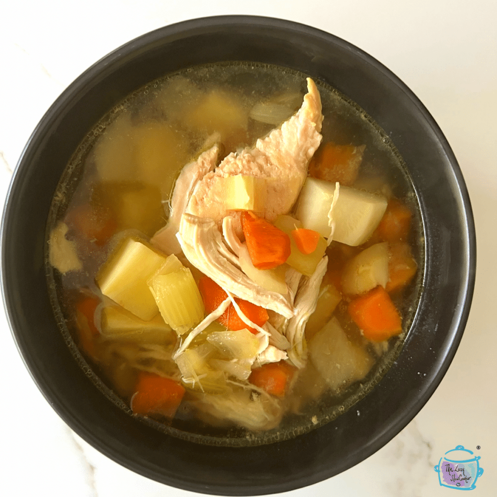 Looking down on a bowl of soup filled with veggies and chicken