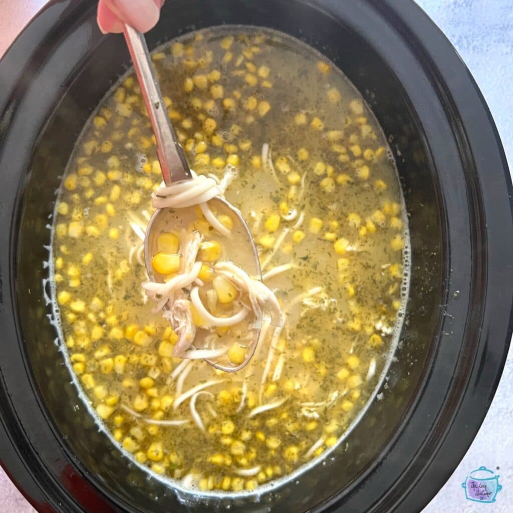 a crockpot full of finished chicken and corn soup after noodles were added