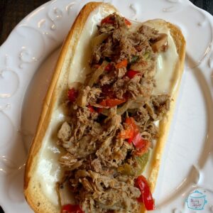 A cheesesteak sandwich laying open on a plate