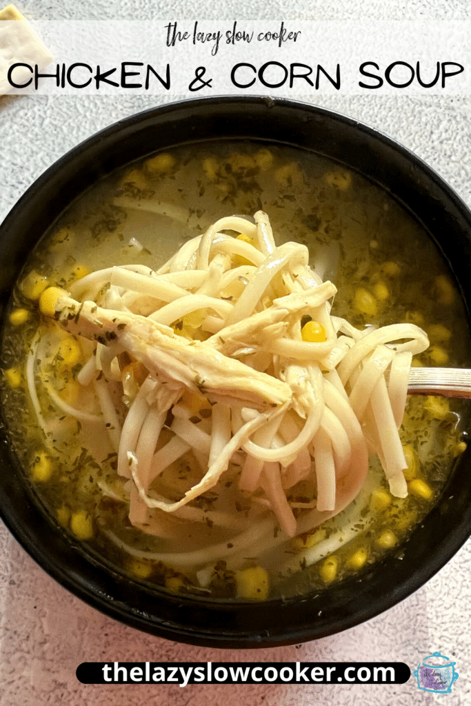 close up of a bowl of chicken and corn soup with noodles being held on a spoon
