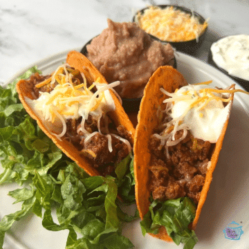 Two hard shell turkey tacos with cheese and sour cream
