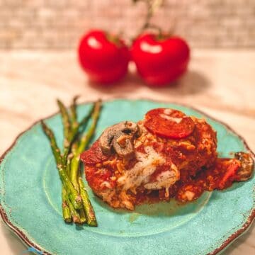 Asparagus and pizza chicken on a turquoise plate