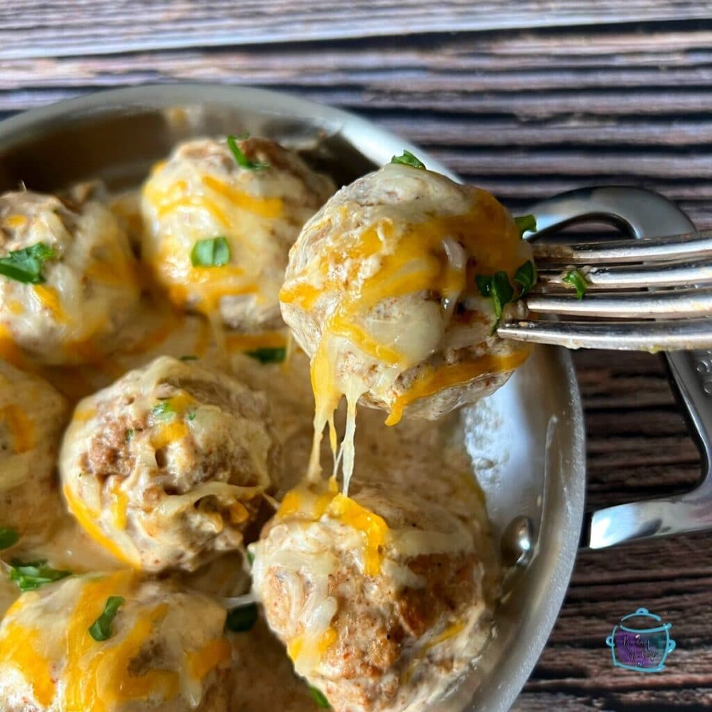 cheesy enchilada meatballs in a pan. one is held on a fork