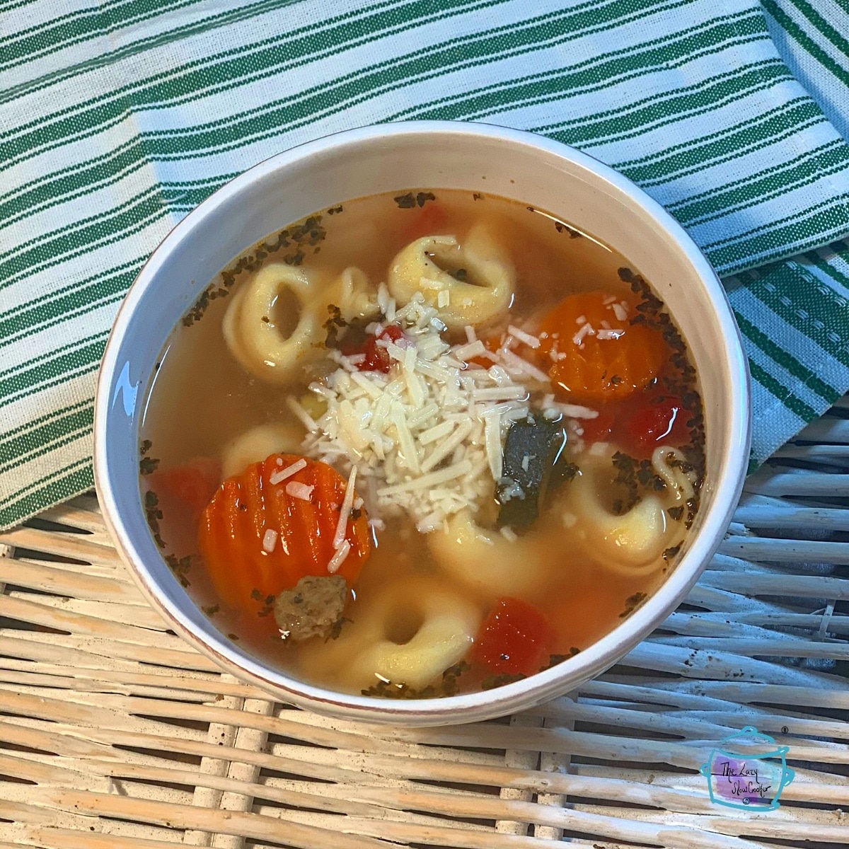 A white bowl of slow cooker turkey sausage and tortellini soup