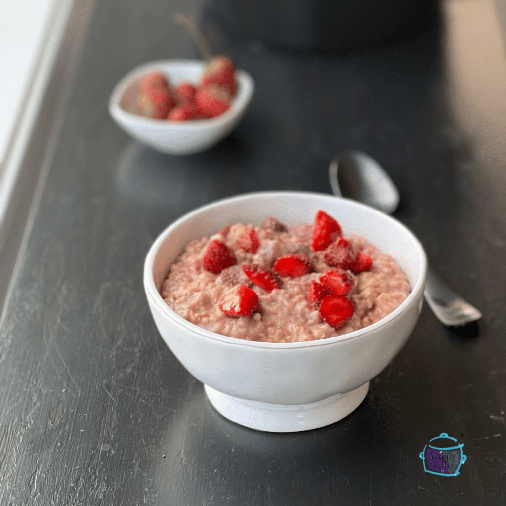 side view of a bowl of finished oatmeal topped with fresh strawberries