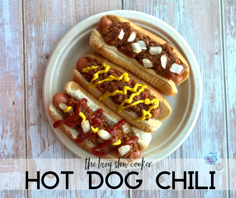 three hot dogs on a plate topped with chili and other toppings