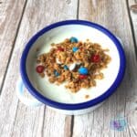 slow cooker peanut butter granola with M&m's on top of yogurt