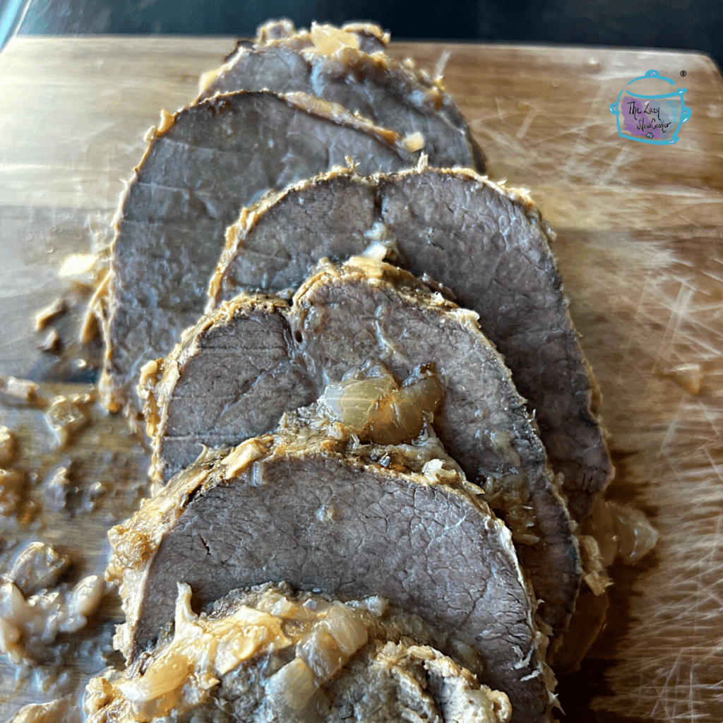 sliced horseradish eye of round roast on a wooden cutting board