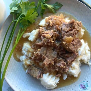 slow cooker horseradish roast over potatoes with gravy and garnish