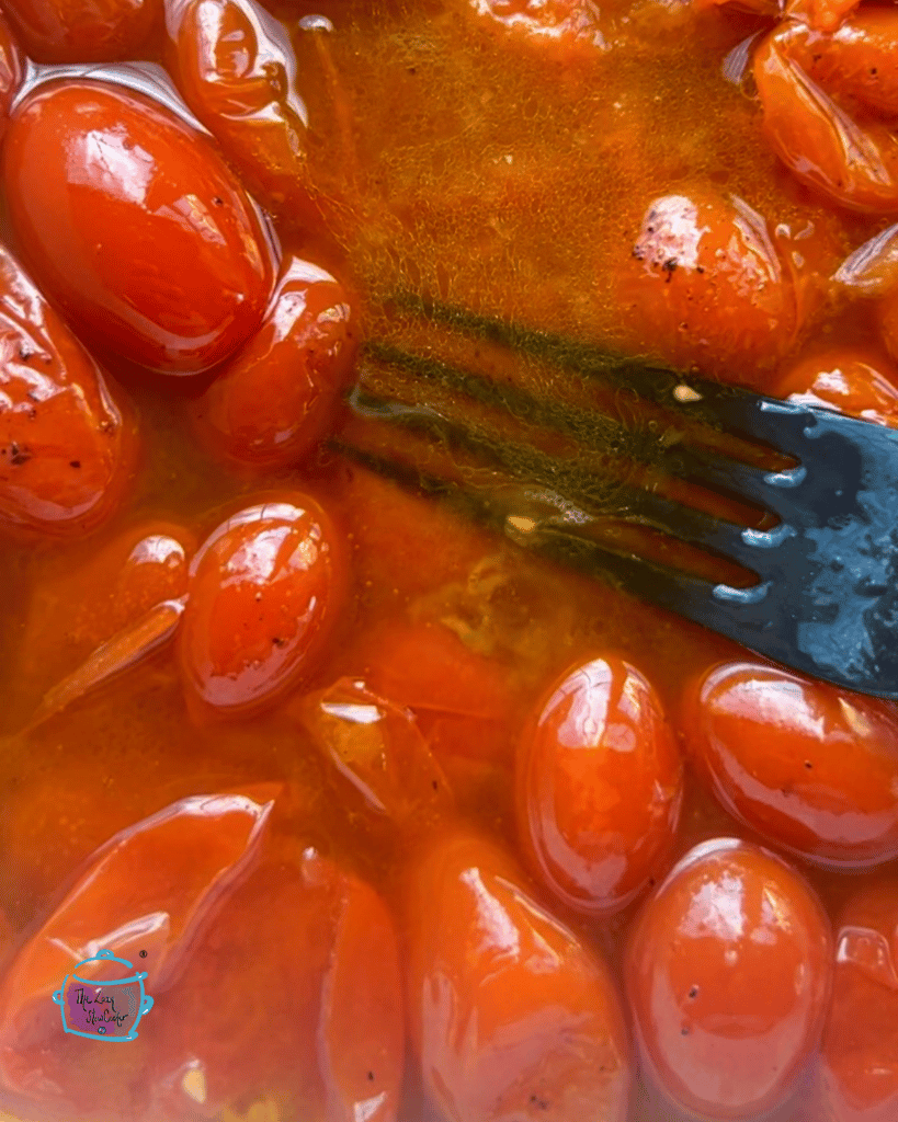 close shot of a slow cooker with some fresh roasted tomatoes and a fork