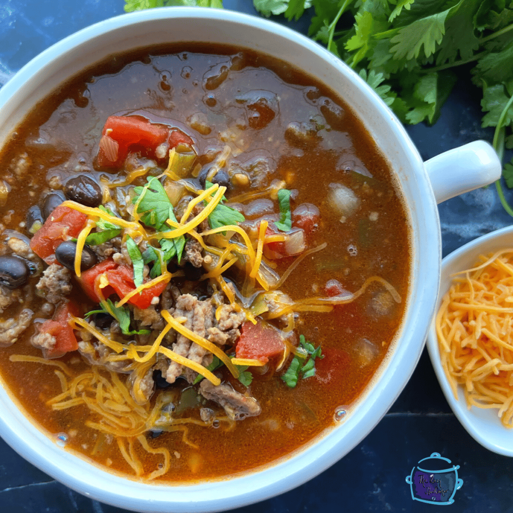 look down on a bowl of slow cooker taco soup topped with shredded cheese