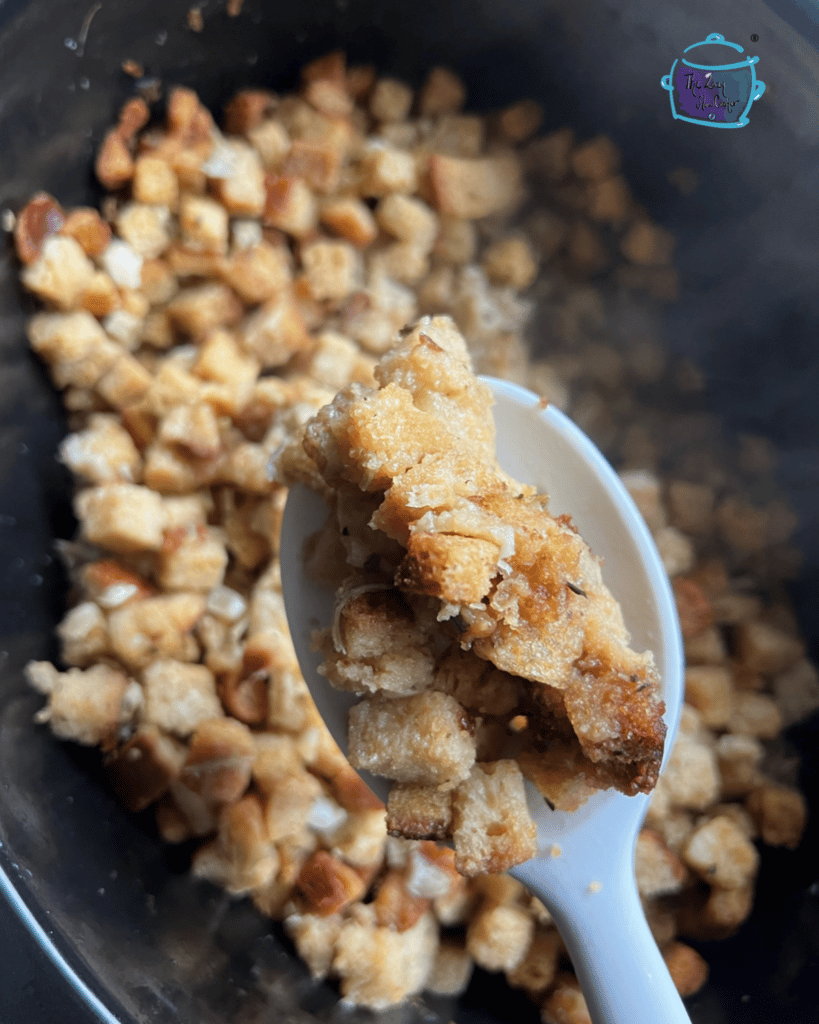 stuffing on a spoon being held over a slow cooker filled with stuffing