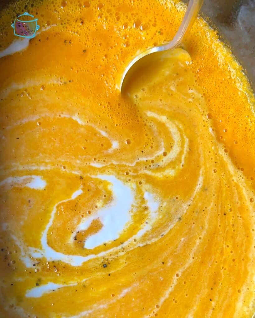 looking down on slow cooker full of carrot ginger soup with coconut cream
