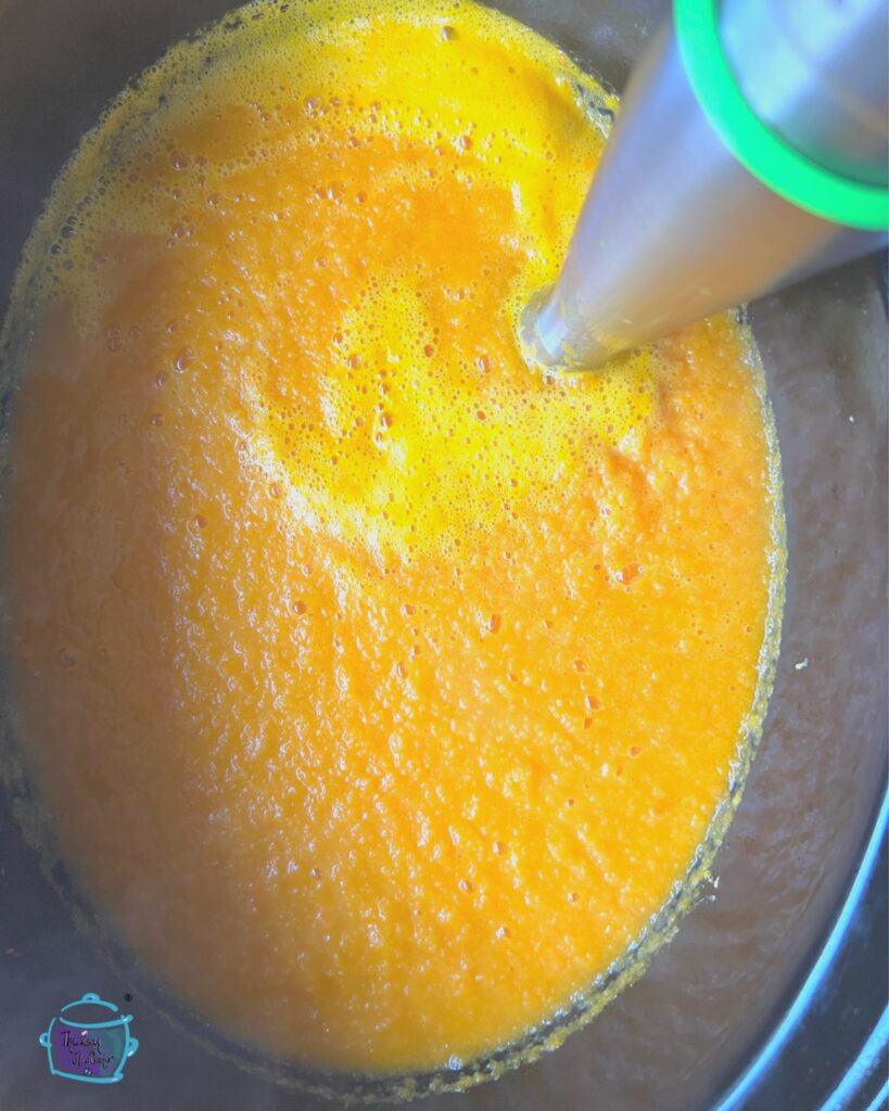 slow cooker carrot soup in crockpot with immersion blender