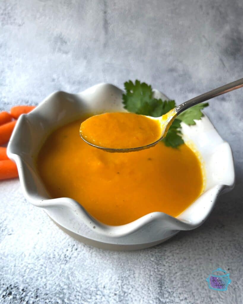 a bowl of ginger carrot soup after slow cooking with some on a spoon