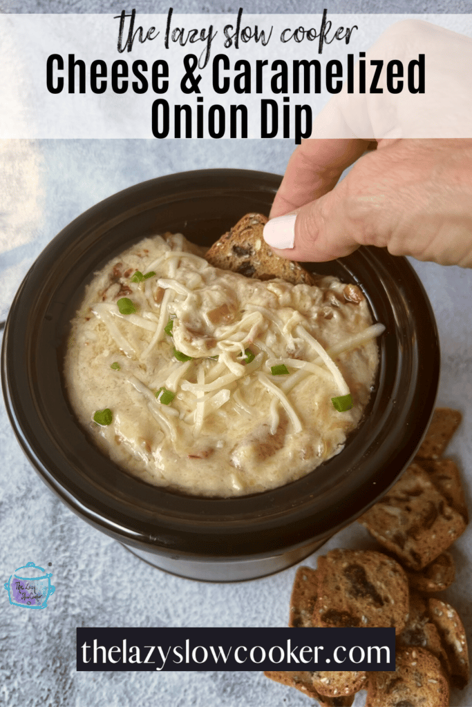 a hand using a cracker to scoop cheesy caramelized onion dip out of a small slow cooker