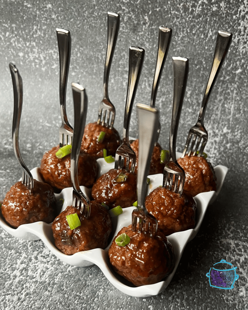 honey bourbon slow cooker meatballs on a tray on mini forks